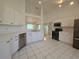 Bright kitchen featuring white cabinets, stainless steel appliances, and white tile floors at 6182 Knotty Pine Ct, Port Orange, FL 32127