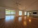 Open living room with ceiling fan, hardwood floors, view into the sunroom, and mirrors on the wall at 6182 Knotty Pine Ct, Port Orange, FL 32127