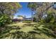 Expansive backyard with lush lawn, mature trees, screened pool, and patio area ideal for outdoor living and entertaining at 6194 Half Moon Dr, Port Orange, FL 32127