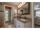 Bathroom with double sink vanity, granite countertops, and an exterior door leading to the backyard at 6194 Half Moon Dr, Port Orange, FL 32127