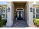 Close-up of the home's entry featuring double doors, stylish lanterns and decorative columns at 6194 Half Moon Dr, Port Orange, FL 32127