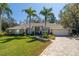 Charming home with a manicured lawn, brick driveway, and lush landscaping featuring palm trees at 6194 Half Moon Dr, Port Orange, FL 32127