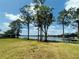 Lush green lawn with mature trees framing a tranquil lake view, providing a serene outdoor setting at 910 N Kepler Rd, Deland, FL 32724