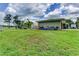 Expansive backyard features a lush lawn, greenhouse, blue barrels, and a partial view of the serene lake at 910 N Kepler Rd, Deland, FL 32724