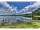 Scenic lake view with calm water reflecting blue skies and fluffy clouds, enhanced by lush green grass in foreground at 910 N Kepler Rd, Deland, FL 32724