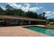 A backyard featuring a pool with a brick patio and a cabana, along with some trees and a basketball court at 910 N Kepler Rd, Deland, FL 32724