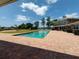 Backyard view of a stunning pool with a basketball hoop, a large patio, and a serene lake backdrop at 910 N Kepler Rd, Deland, FL 32724