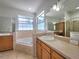 This primary bathroom features double sinks, a large soaking tub, a walk-in shower and bright natural light at 1072 Ceasars Ct, Mount Dora, FL 32757