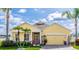 Charming, one-story, yellow home with a well-manicured lawn, palm trees, and an attached two-car garage at 112 Coral Reef Ct, Sanford, FL 32771