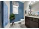 Charming half bathroom with blue accent wall, granite countertop, and natural light from the window at 1219 Victoria Hills N Dr, Deland, FL 32724