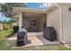 Outdoor brick patio area featuring two grills and a screened-in patio with table and chairs at 1504 Ginger Snap, Deland, FL 32720