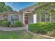 Charming home exterior with a red front door, arched windows, column, and well-maintained landscaping at 1504 Ginger Snap, Deland, FL 32720