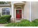 Inviting front entrance with a red door, decorative glass, stone accents, and lush greenery at 1504 Ginger Snap, Deland, FL 32720