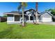 Charming blue home with a well-manicured lawn, complemented by two palm trees and a two-car garage at 1842 W Cooper Dr, Deltona, FL 32725