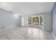 Spacious living room featuring tile floors, large windows, and a convenient front door at 1842 W Cooper Dr, Deltona, FL 32725