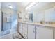 Well-lit bathroom with a double sink vanity, framed mirror, and glass-enclosed shower at 1860 Turnbull Lakes Dr, New Smyrna Beach, FL 32168