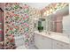 Bright bathroom featuring floral wallpaper, white cabinets, and a large mirror at 1926 Ocean Shore Blvd # 3050, Ormond Beach, FL 32176
