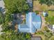 Overhead shot of a charming home with blue metal roof surrounded by lush greenery and palm trees, showcasing curb appeal at 1927 Orange Tree Dr, Edgewater, FL 32141
