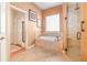 Bright bathroom featuring a soaking tub, tile flooring, a walk-in shower, and two entry doors at 202 Westcott Ct, Deland, FL 32724