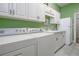 Bright laundry room with white appliances, ample storage, and green accent wall at 202 Westcott Ct, Deland, FL 32724