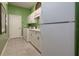 Well-equipped laundry room features white cabinetry, appliances, and green walls at 202 Westcott Ct, Deland, FL 32724