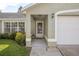 Covered front entryway with beautiful landscaping and a white door with glass inset panels at 227 Heronwood Cir, Deltona, FL 32725