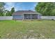View of the backyard with a well-maintained lawn, white fencing, and covered patio at 2355 W Orange Rd, Deland, FL 32724