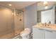 Bathroom featuring a glass-enclosed shower and vanity with a marble countertop and a round mirror at 241 Riverside Dr # 2110, Daytona Beach, FL 32117
