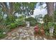 Secluded backyard featuring lush landscaping, a flagstone pathway, and a comfortable seating area under the shade of a mature tree at 2427 Beck Cir, Deltona, FL 32738