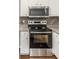 Close-up of the stainless steel oven and cooktop with microwave and decorative backsplash at 2466 Candlewick St, Deltona, FL 32738