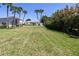 Expansive backyard with lush green lawn, mature palm trees, and a view of the home's rear facade at 2542 S Peninsula Dr, Daytona Beach, FL 32118