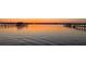 Calm waterfront with vibrant sunset reflecting on the water and silhouetting a pier in the distance at 2542 S Peninsula Dr, Daytona Beach, FL 32118