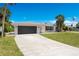 Home featuring an expansive driveway, black garage door, and meticulously maintained lawn at 2565 S Peninsula Dr, Daytona Beach, FL 32118