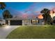 Charming home exterior with well-maintained lawn, black garage door, and lovely sunset at 2565 S Peninsula Dr, Daytona Beach, FL 32118