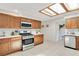 Bright kitchen featuring stainless steel appliances, wooden cabinets, quartz counters, and skylight at 2565 S Peninsula Dr, Daytona Beach, FL 32118