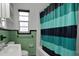 Bathroom with a black and blue striped shower curtain and green ceramic tiling at 263 Seaview Ave, Daytona Beach, FL 32118