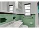 Cozy bathroom with green ceramic tiling, white fixtures, and a small window at 263 Seaview Ave, Daytona Beach, FL 32118
