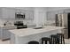 Modern kitchen features sleek stainless steel appliances, gray cabinets, an island with bar seating, and quartz countertops at 2743 Gentle Rain Dr, Davenport, FL 33837