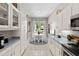 Well-lit kitchen with white cabinetry, neutral countertops, and modern appliances overlooking the dining area at 3140 Kailani Ct, Ormond Beach, FL 32174
