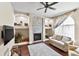 Inviting living room featuring a stone fireplace, built-in shelving, ceiling fan, and hardwood floors at 3470 Tesoro Cir, New Smyrna Beach, FL 32168