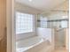 Bright bathroom featuring a soaking tub next to a glass shower with patterned wallpaper at 38 Lake Walden Trl, Ormond Beach, FL 32174
