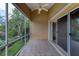 A tiled, screened-in porch with a ceiling fan overlooking a lake with tropical foliage at 38 Lake Walden Trl, Ormond Beach, FL 32174