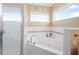A bright bathroom featuring a large soaking tub, walk-in shower, and two windows for lots of natural light at 3817 Islamorada Dr, Ormond Beach, FL 32176