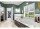 Elegant bathroom featuring a soaking tub with jets, decorative stone accents, and bright natural light from plantation shutters at 4 Huntsman Look, Ormond Beach, FL 32174