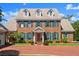 Two-story brick home showcasing lush green landscaping, a red brick driveway, and decorative dormer windows at 4 Huntsman Look, Ormond Beach, FL 32174