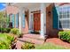 A welcoming orange front door with seasonal wreath is surrounded by white columns and manicured landscaping at 4 Huntsman Look, Ormond Beach, FL 32174