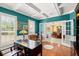 Bright home office with teal walls, white trim, coffered ceiling, desk, chair, and views of the dining room at 4 Huntsman Look, Ormond Beach, FL 32174
