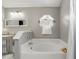 Bathroom features a relaxing bathtub with a mirrored accent, updated light fixtures, and neutral wall color at 417 Jeffers St, Deltona, FL 32725