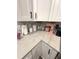 White kitchen features quartz countertops, cabinetry with black hardware, and a mosaic tile backsplash at 4339 Northern Dancer Way, Orlando, FL 32826