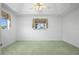 Light-filled bedroom featuring a tray ceiling, neutral paint, plush carpet, and a charming window with floral curtains at 5097 Nw 19Th Pl, Ocala, FL 34482